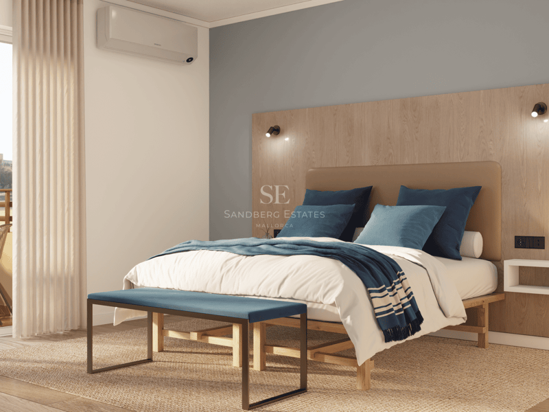 Chambre lumineuse avec lit double, tête de lit en bois et accès à un balcon ensoleillé.