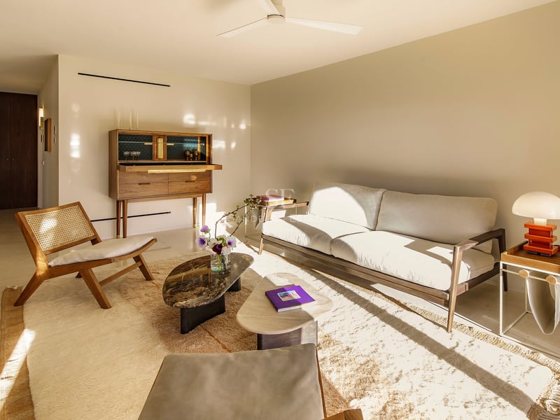 Helles Wohnzimmer mit Mid-Century-Möbeln, Marmortisch, Holzschrank und sonnendurchflutetem cremefarbenem Sofa.