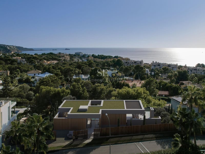 Vue aérienne d'une villa contemporaine avec toit végétalisé et façade en bois surplombant la mer Méditerranée.