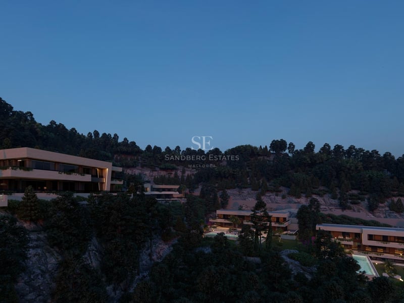 Villas de luxe nichées dans une colline verdoyante avec fenêtres éclairées sous un ciel de crépuscule.
