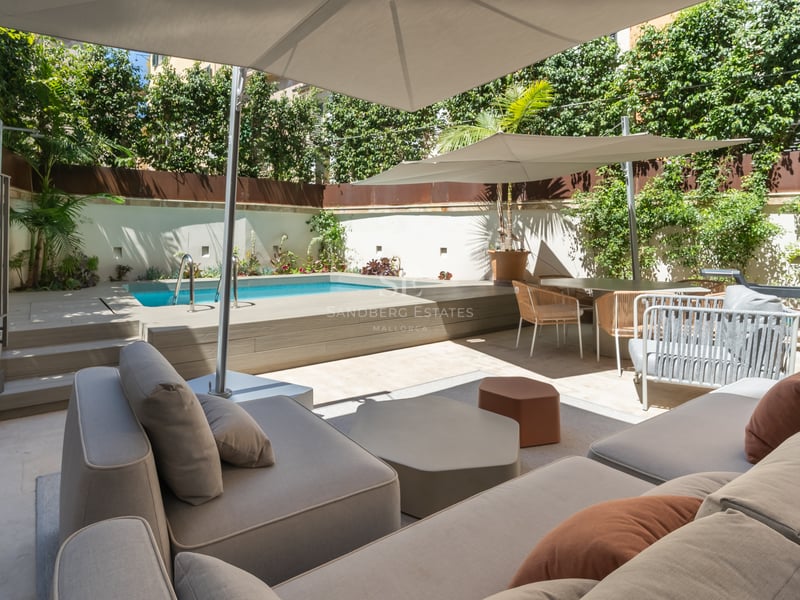 Terrasse moderne avec petite piscine, salon extérieur sous parasols et plantes verdoyantes pour l'intimité.