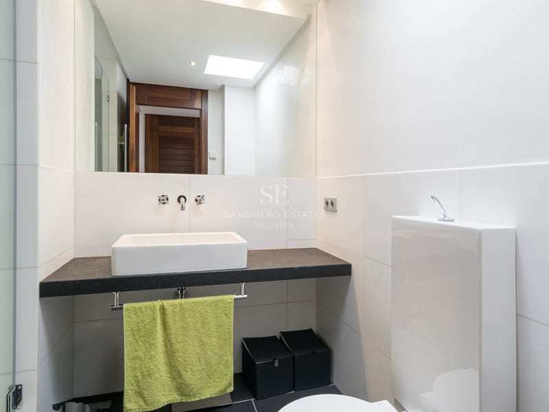 Contemporary bathroom featuring a white vessel sink on a dark stone vanity with a large wall mirror.