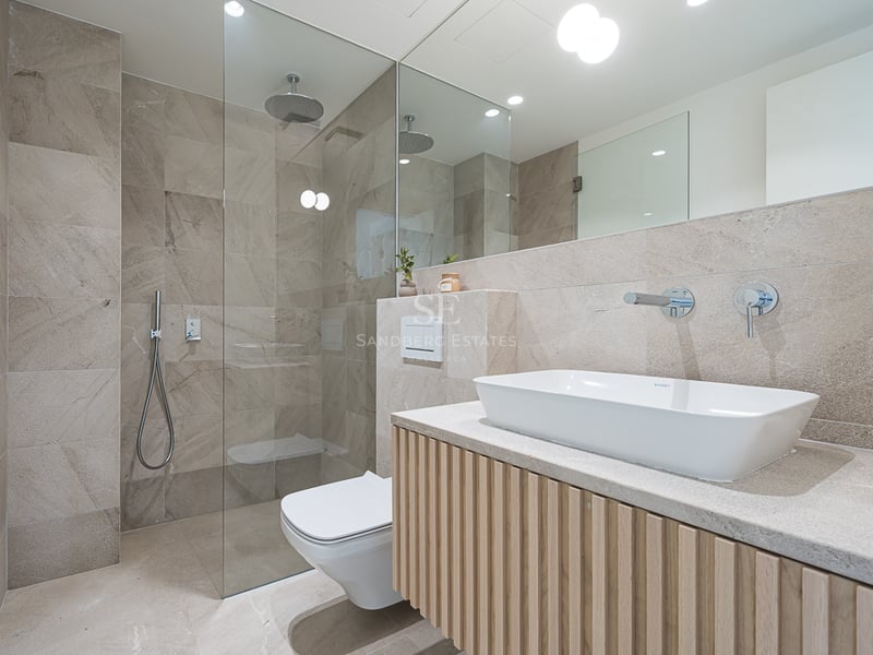 Contemporary bathroom featuring natural stone tiling, a glass walk-in rain shower, and a slatted wood floating vanity.