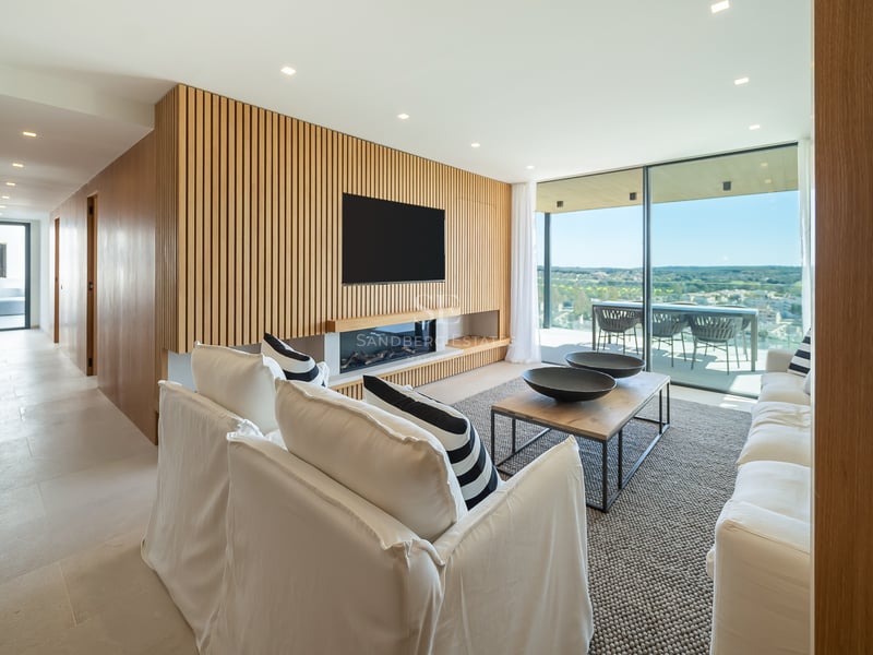 Salon moderne avec mur en bois à claire-voie, cheminée linéaire, canapés blancs et grandes baies vitrées.