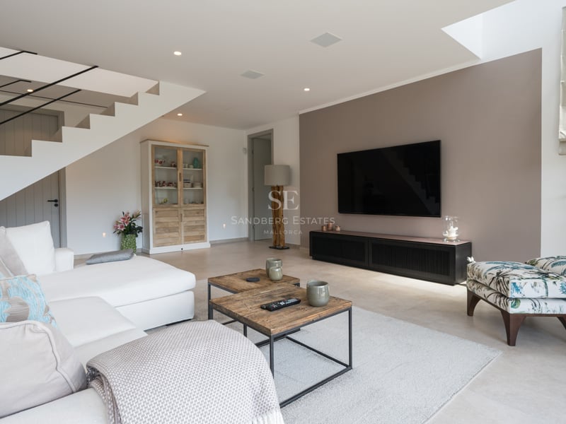 Salon spacieux et lumineux avec de grandes baies vitrées et accès à un balcon offrant une vue panoramique sur la mer. Mobilier moderne dans des tons neutres.