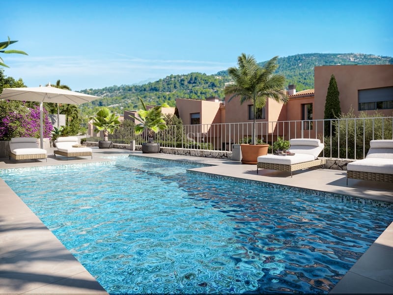 Turkos pool med solstolar och palmer med utsikt över gröna berg under en klarblå himmel.