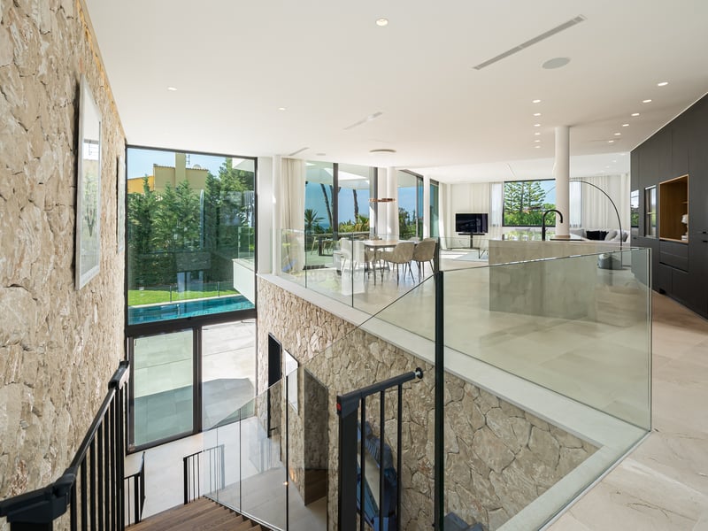 Vue en hauteur d'un salon et d'une salle à manger modernes à aire ouverte avec un mur en pierre naturelle et du verre.