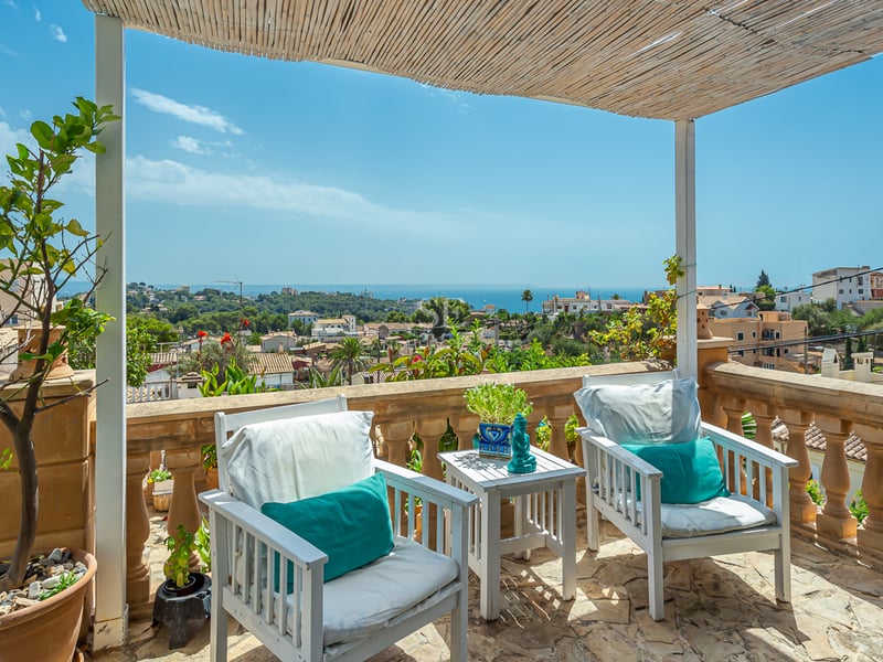 View of a modern villa with an infinity pool, stylish sun loungers, and minimalist architecture. Lush garden and blue sky in the background.