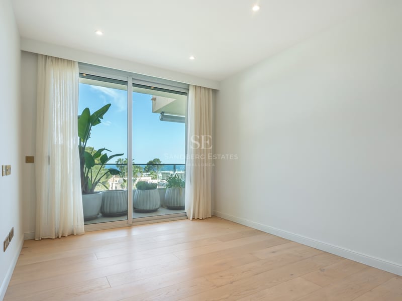 Empty modern room featuring light wood floors and large sliding glass doors opening to a terrace with sea views.