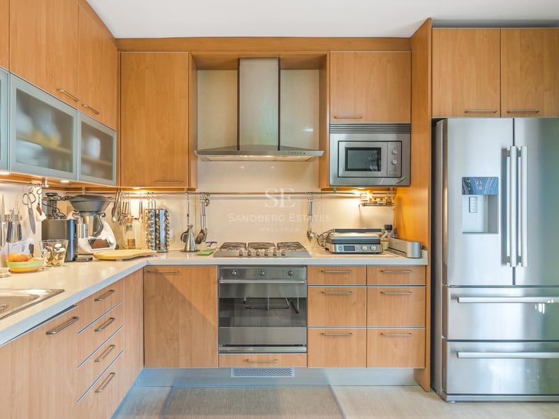 Zeitgenössische Küche mit hellen Holzschränken, Edelstahlgeräten und integrierter Unterbaubeleuchtung.