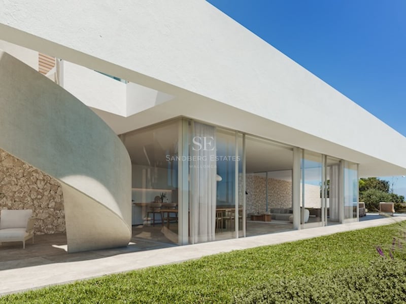 Villa blanche moderne avec un escalier en colimaçon en béton, des baies vitrées et un mur en pierre naturelle.