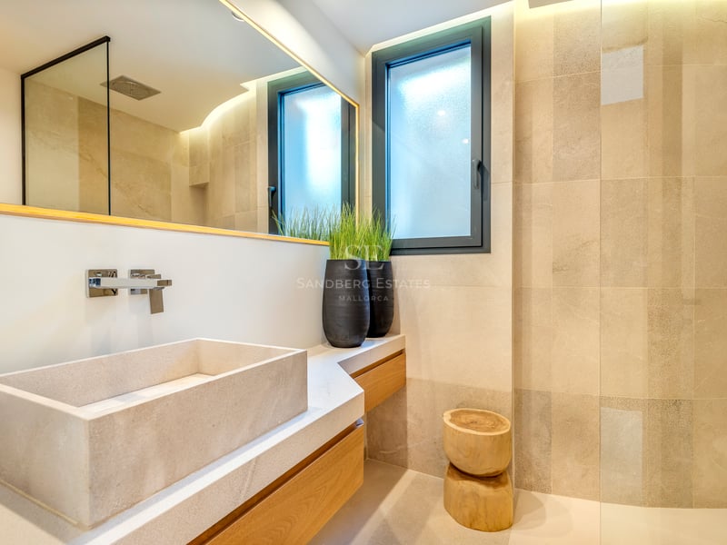 Salle de bains contemporaine avec vasque rectangulaire en pierre sur meuble en bois et éclairage tamisé.