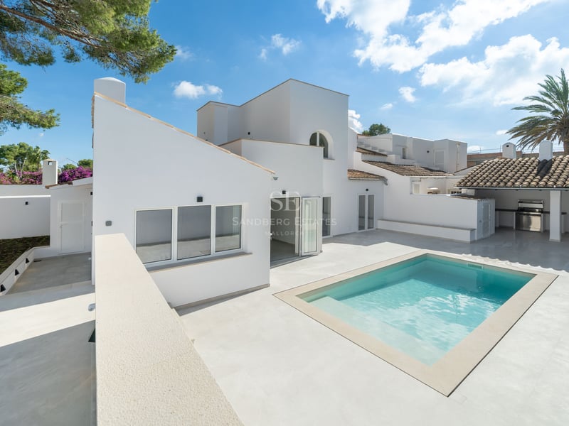 Villa méditerranéenne moderne blanche avec piscine étincelante, terrasse en pierre et cuisine extérieure.