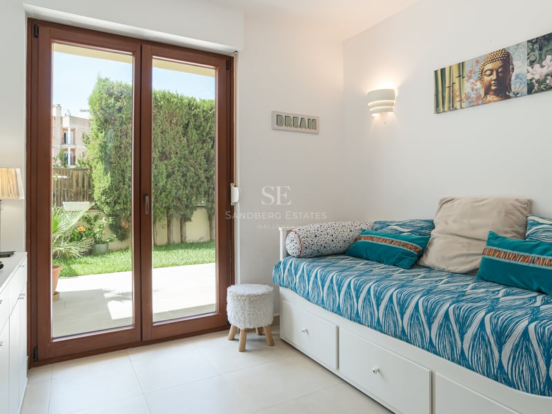 Chambre d'amis moderne avec un lit gigogne blanc et des portes vitrées en bois ouvrant sur un jardin privé.