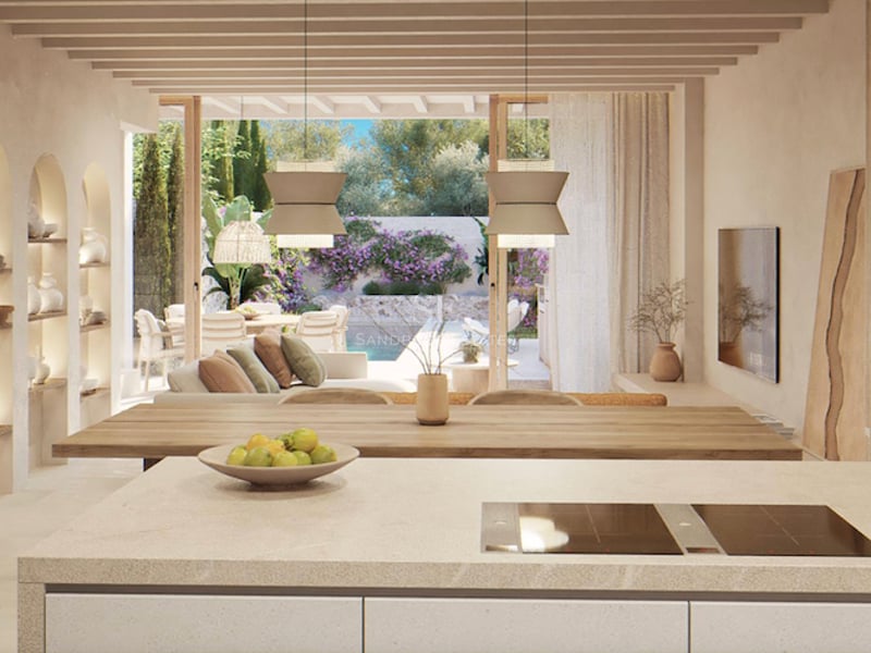 Espace ouvert avec îlot de cuisine, poutres en bois et vue sur une terrasse avec piscine et jardin.