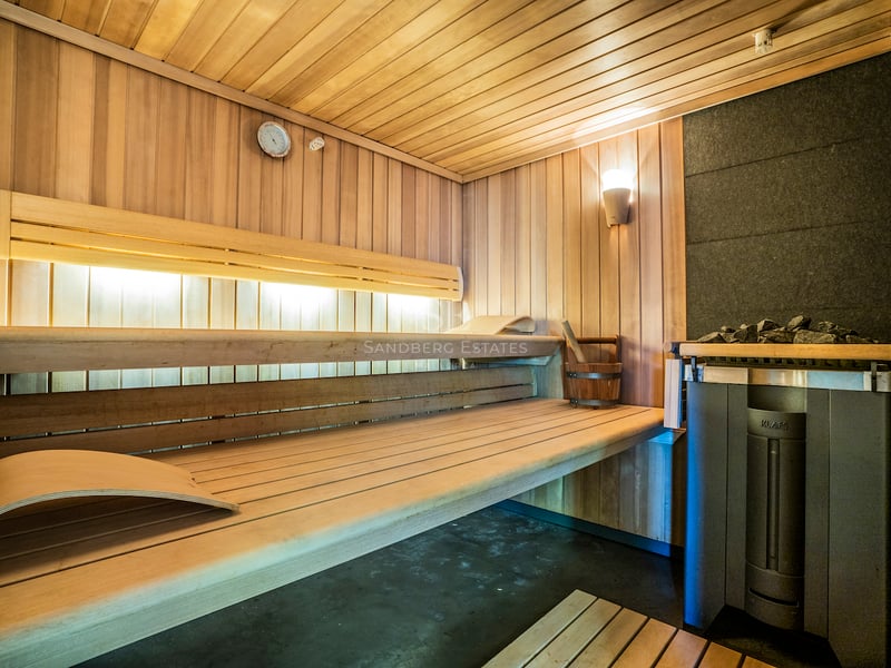 Innenansicht einer modernen Holzsauna mit mehrstufigen Bänken, Ambientebeleuchtung und KLAFS-Saunaofen.