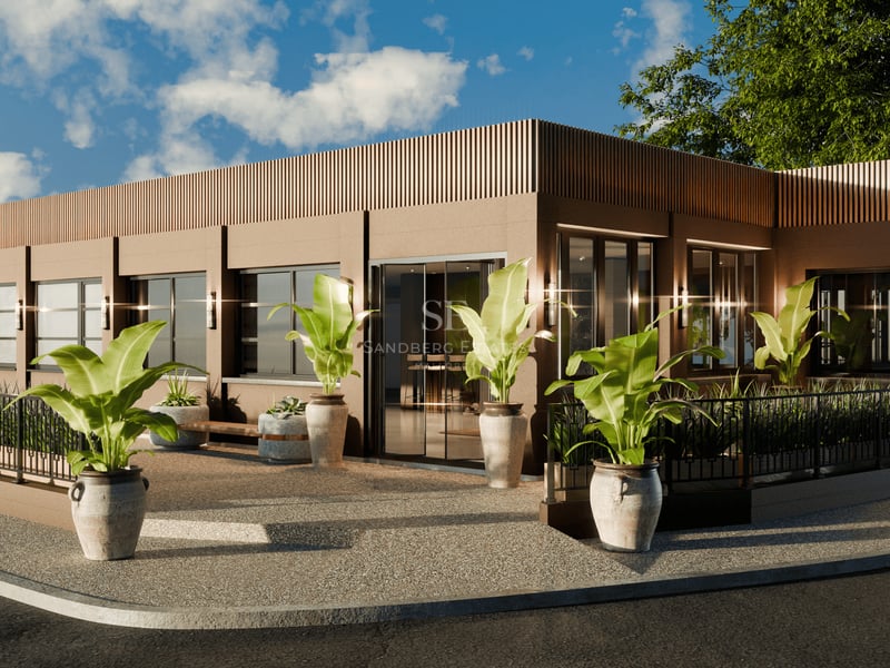 Façade de bâtiment moderne aux tons terreux avec de grandes fenêtres et des plantes tropicales dans des pots en pierre.