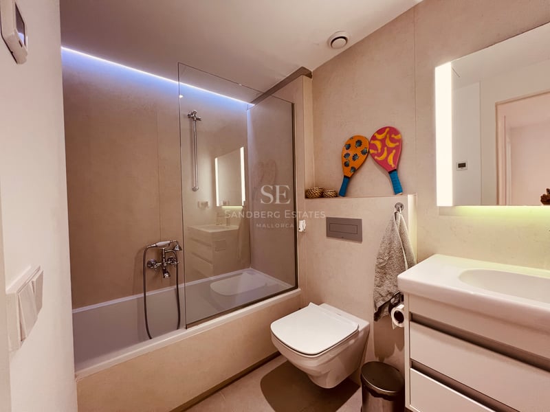Salle de bain contemporaine avec baignoire, paroi vitrée, toilettes suspendues et éclairage LED intégré.