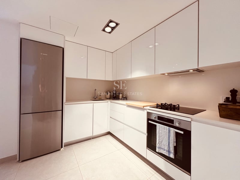 Cuisine minimaliste blanche laquée avec four encastré, plaque de cuisson en verre et éclairage encastré au plafond.