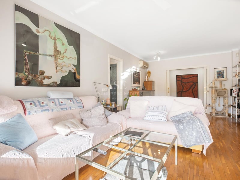 Helles Wohnzimmer mit rosa Sofas, Glastisch, poliertem Parkett und großen Wandgemälden.