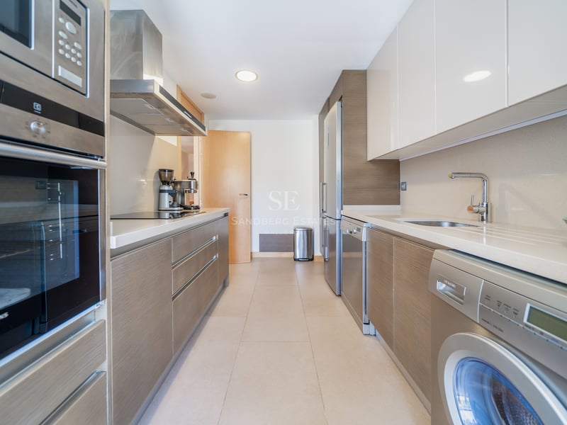 Cuisine en couloir avec meubles en bois et blanc, équipée d'appareils Siemens en acier inoxydable.