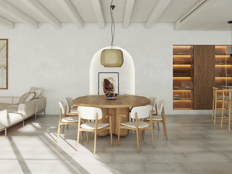 Salle à manger moderne avec table ronde en chêne, niche voûtée et plafond à poutres blanches dans une villa de luxe.