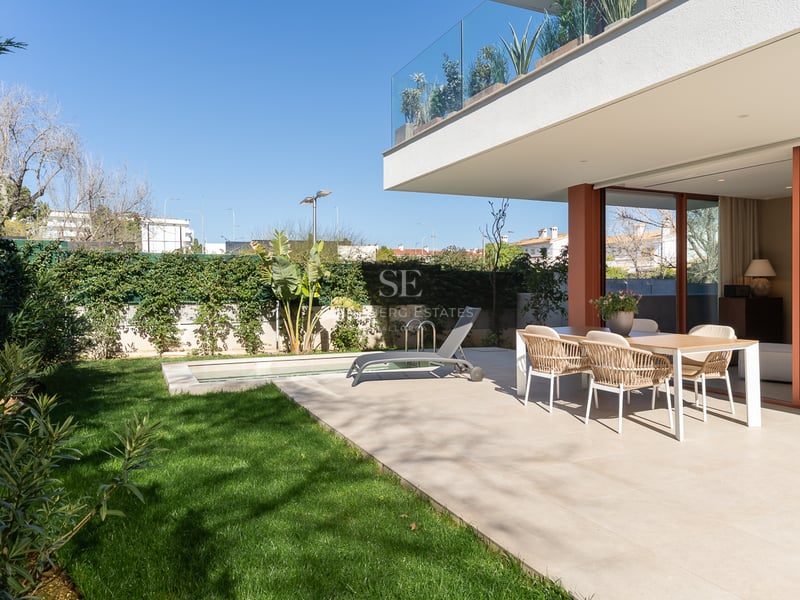 A contemporary outdoor terrace featuring a dining set, sun lounger, private lawn, and small pool under a clear blue sky.