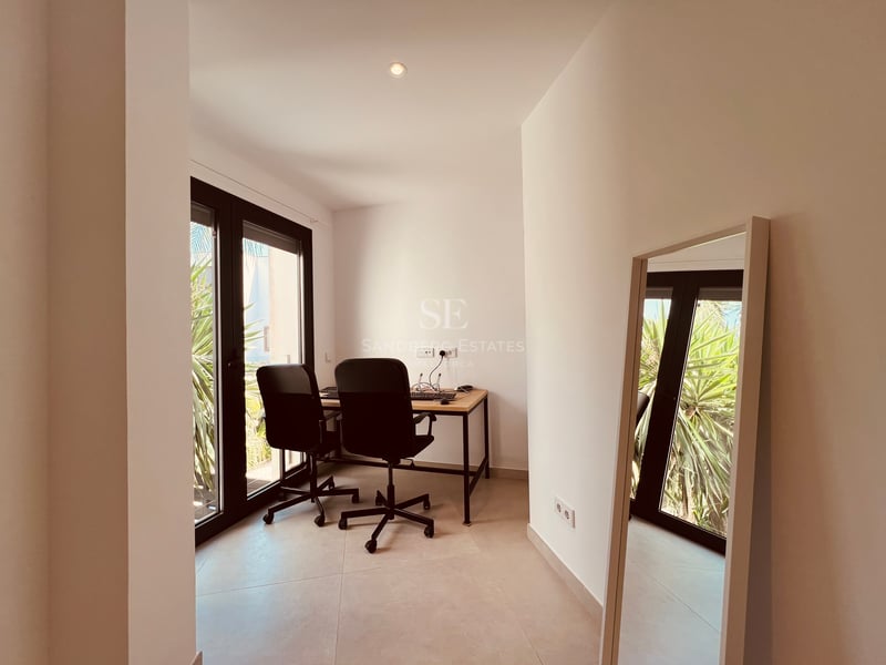 Bureau contemporain lumineux avec table en bois, chaises ergonomiques et grandes baies vitrées donnant sur le jardin.