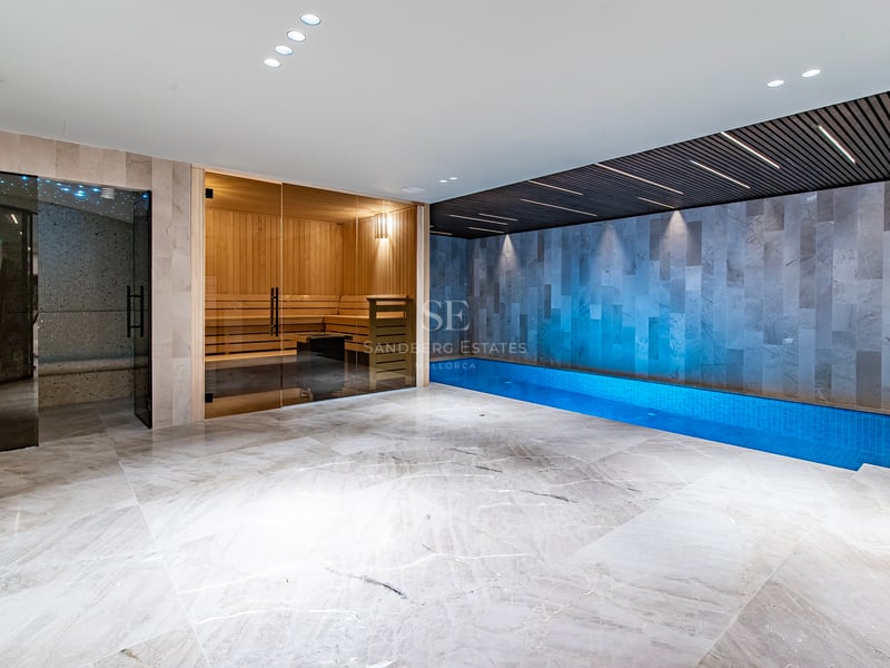 Espace spa intérieur moderne avec sol en marbre, sauna vitré et piscine intérieure avec éclairage d'ambiance.