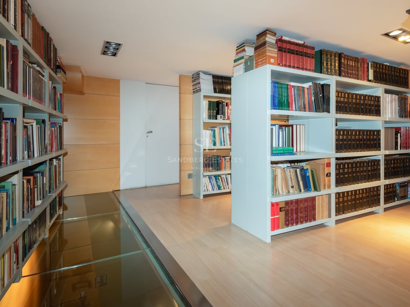 Bibliothèque moderne avec étagères blanches et passerelle en verre transparent sur parquet en bois clair.