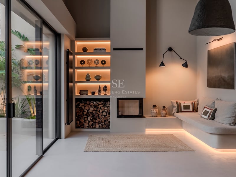 Salon minimaliste moderne avec canapé intégré, éclairage encastré, cheminée et grandes baies vitrées coulissantes.