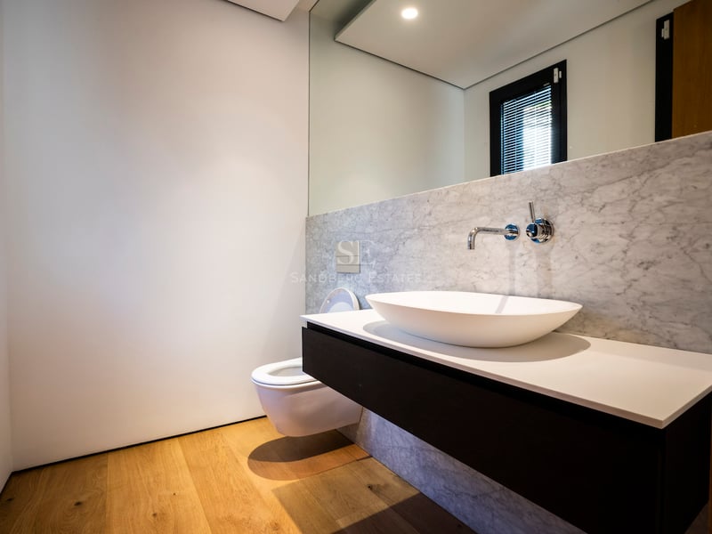 Zeitgenössisches Badezimmer mit Aufsatzwaschbecken auf schwebendem Waschtisch, Steinwänden und Holzboden.