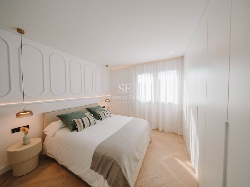 Chambre principale moderne avec lit double, moulures murales décoratives et parquet clair en point de Hongrie.