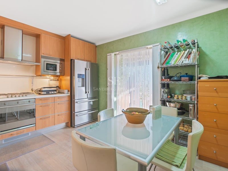 Zeitgenössische Küche mit hellen Holzfronten, Edelstahlgeräten und einem Esstisch aus Glas.