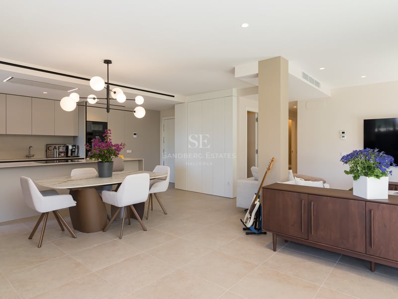 Bright open-concept room featuring a marble dining table, contemporary globe chandelier, and sleek integrated kitchen.
