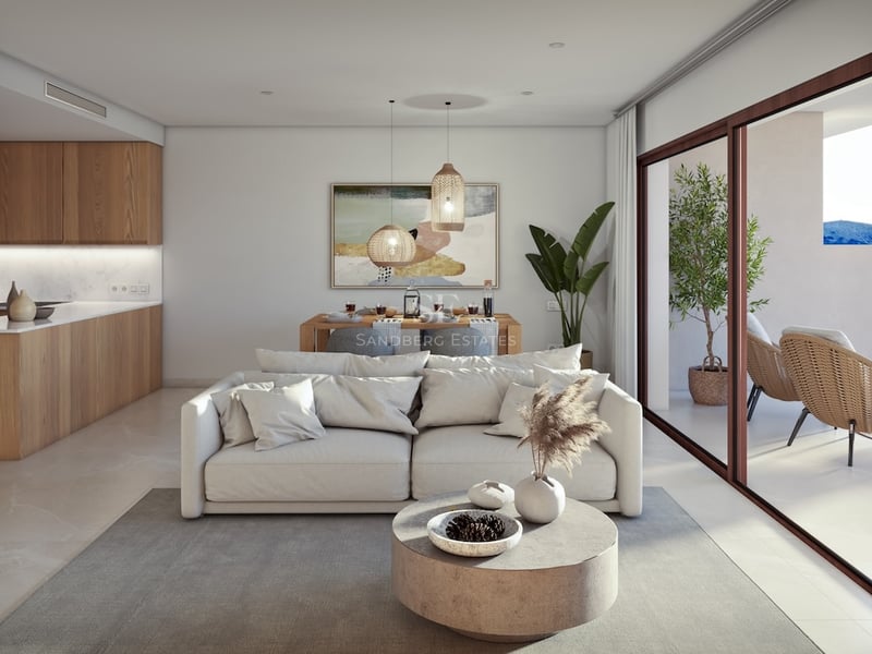 Modern living room with white sofa, stone coffee table, and large glass doors opening to a sunny terrace.