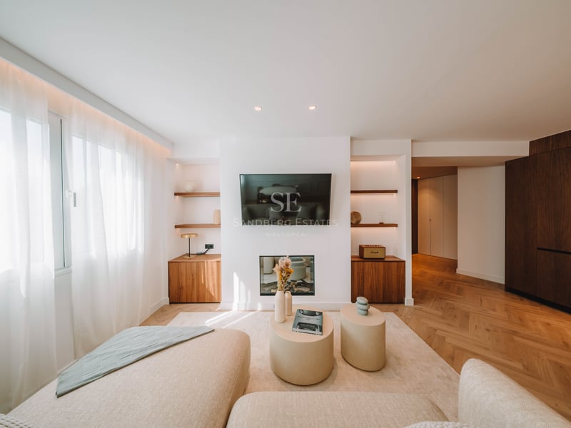 Salon lumineux avec TV murale, cheminée, parquet en point de Hongrie et canapés beiges.