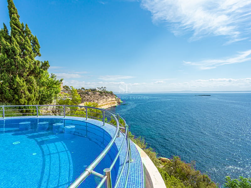 Grand balcon avec vue sur la mer, mobilier moderne, garde-corps en verre. Espace lumineux et élégant. Détails architecturaux design.