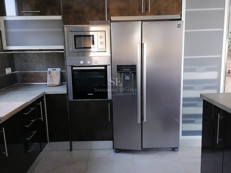 Cuisine contemporaine avec placards brillants, électroménager Bosch intégré et grand réfrigérateur en inox.