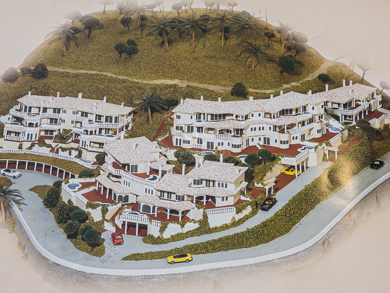 Spacious living room with large windows, light wood floors, modern furniture and views of the pool and lush garden.