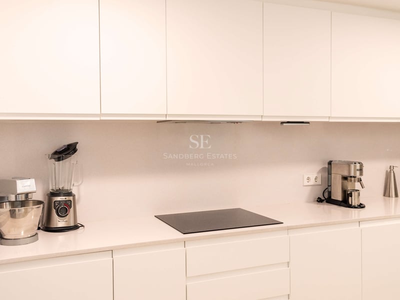 Zeitgenössische weiße Küche mit grifflosen Schränken, Quarzarbeitsplatte und Induktionskochfeld.