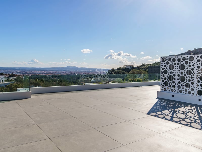 Grand toit-terrasse moderne avec dalles grises, garde-corps en verre et écran blanc perforé dominant la ville.