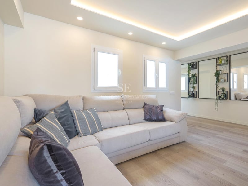 Modernes Wohnzimmer mit großem cremefarbenem L-Sofa, hellem Holzboden und LED-Deckenbeleuchtung.