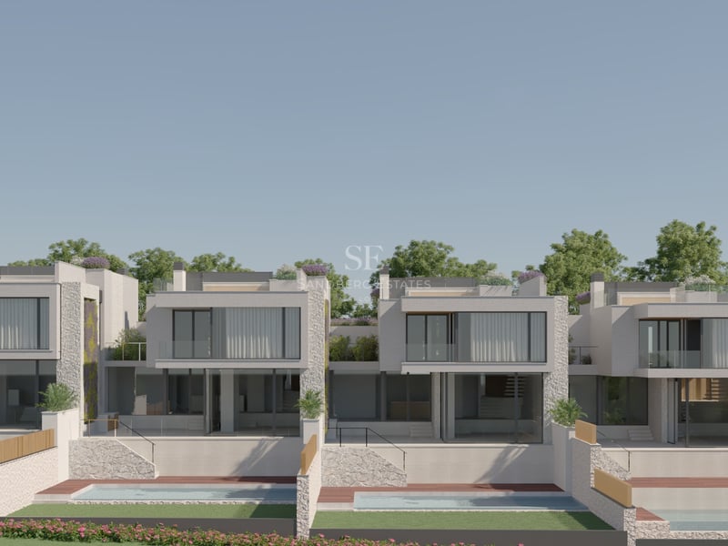 Modern two-story villas featuring expansive glass facades, natural stone walls, and private gardens under a clear sky.