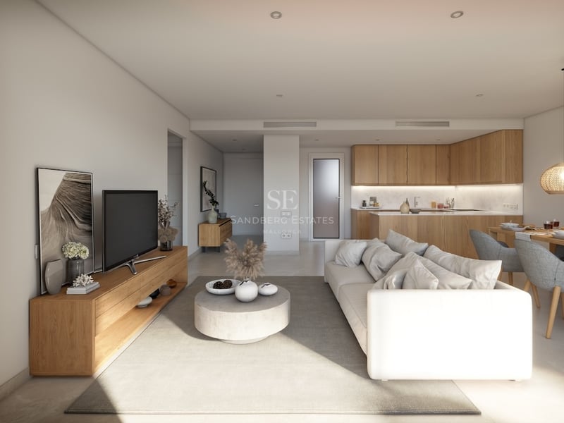 Bright modern living room with a white sofa, wooden furniture, and an integrated kitchen in the background.