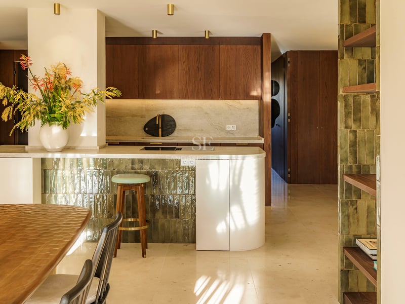 Moderne Küche mit Marmorinsel und grünen Fliesen, Holzhocker und Schränken aus Walnussholz.