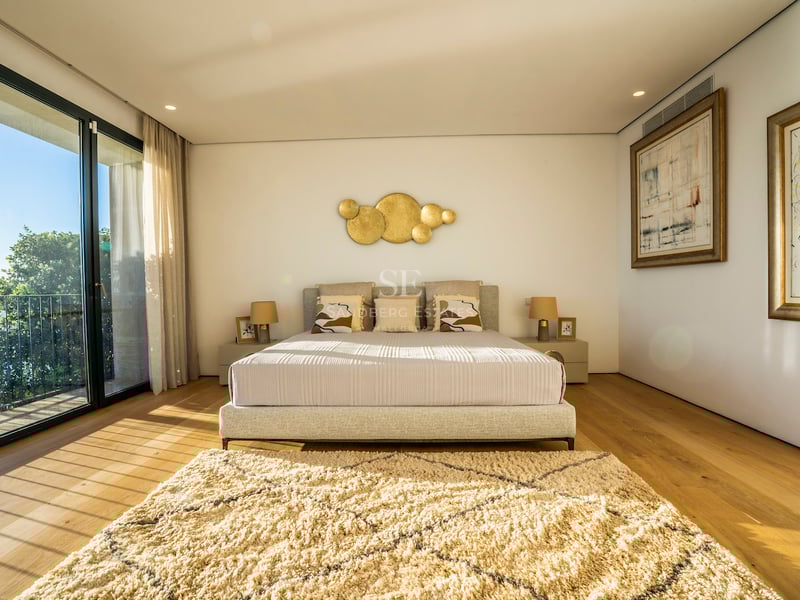 Modernes Hauptschlafzimmer mit Eichenparkett, bodentiefen Glasfronten und Zugang zur Terrasse mit Blick auf das Mittelmeer.