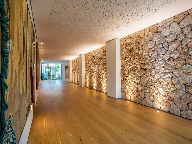 Moderner Innenflur mit strukturierter Steinwand, Bodenstrahlern und hellem Eichenparkett.