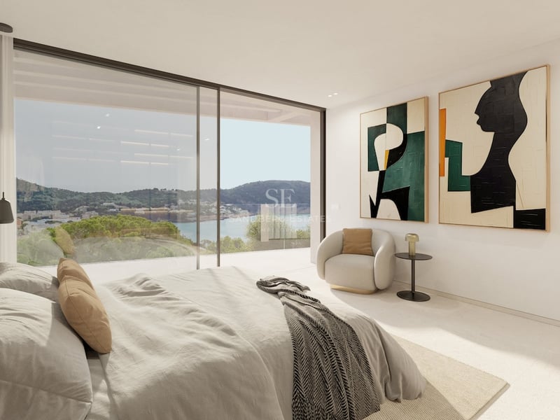 Modernes Hauptschlafzimmer mit großen Glasfronten und Blick auf die Küste und das Meer.