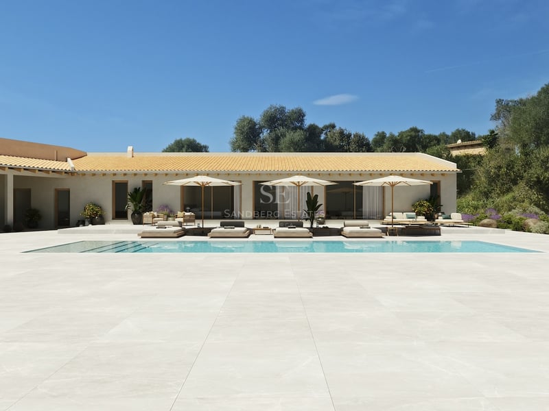 Grande piscine et vaste terrasse claire devant une villa méditerranéenne sous un ciel bleu pur.